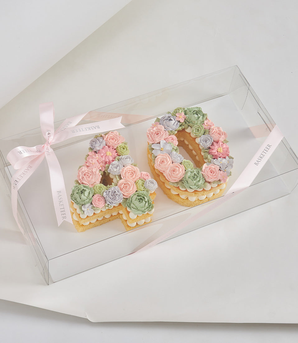 Pastel floral number cake set forming "40" with piped buttercream flowers in pink, lavender, and green