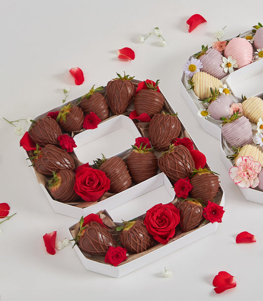 Letter-shaped gift box with chocolate-covered strawberries and red roses for birthday celebrations