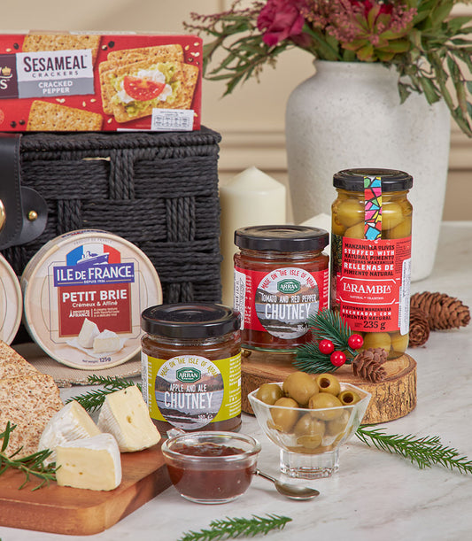 Luxury gourmet hamper with French brie, artisan crackers, imported olives, and chutneys in black woven basket
