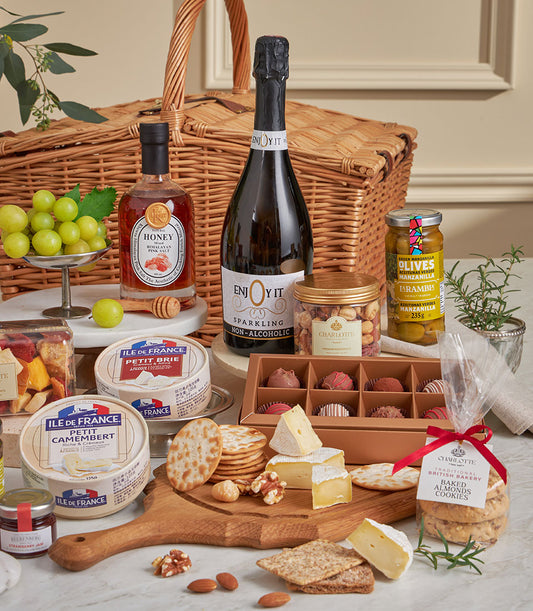 Luxury wicker picnic basket with gourmet cheeses, crackers, chocolates, sparkling beverage, and artisan almond cookies