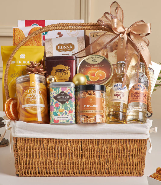 Premium New Year gift hamper with almond cookies, cocoa, herbal tea, honey syrup and gourmet snacks in woven wicker basket