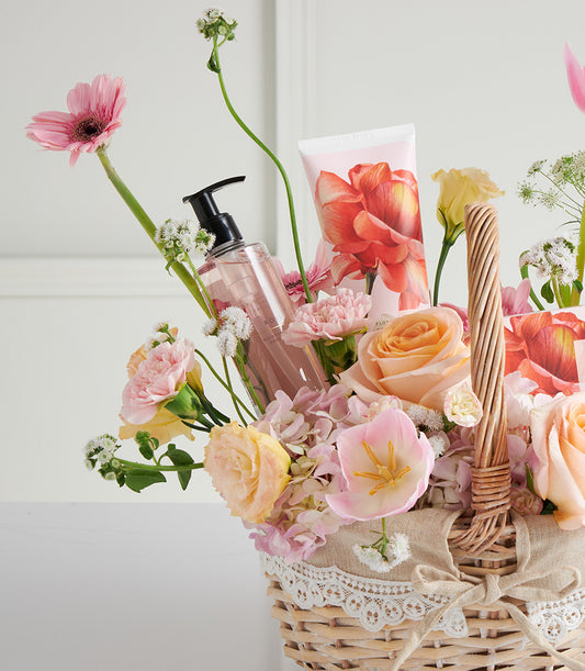 Mother's Day wicker basket with fresh pastel roses, gerberas, tulips, and spa care products with floral packaging