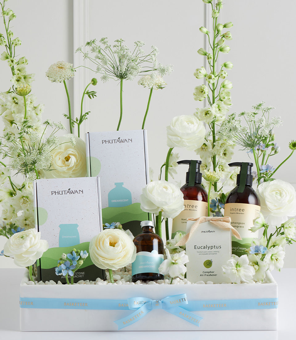 White wellness gift basket with spa products, fresh white flowers, and blue accents for Mother's Day