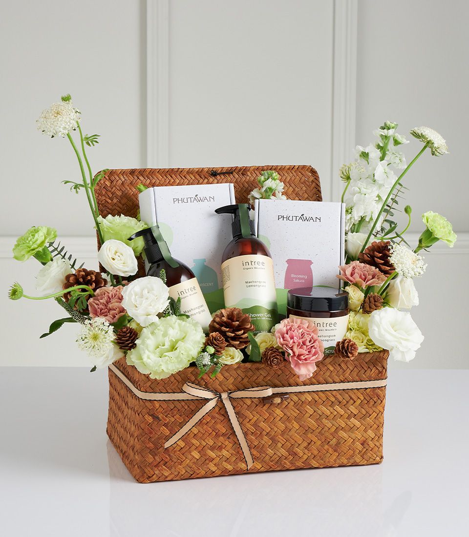 Woven straw gift basket with lemongrass spa products, fresh white and pink flowers for Mother's Day