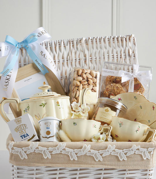 Luxury Mother's Day tea gift basket with cream floral teapot, matching cups, gourmet treats, and premium tea selection