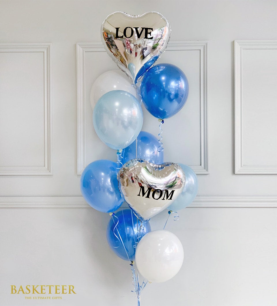 Blue and white balloon bouquet with silver heart balloons spelled "LOVE MOM" tied with blue ribbons