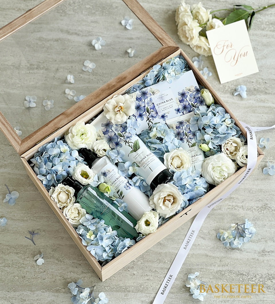 Light blue hydrangeas and white roses with spa products in wooden gift box, Mother's Day gift set
