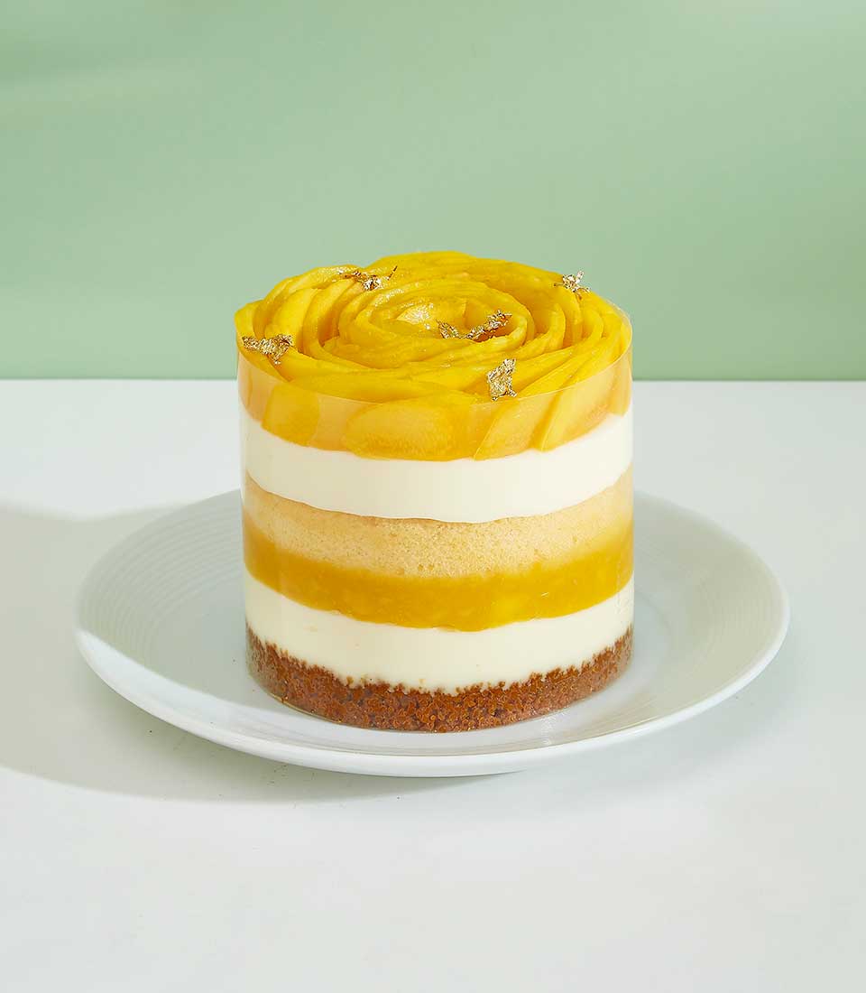 Swirled mango mini layer cake with gold leaf on white plate, Charlotte Bakery artisan dessert