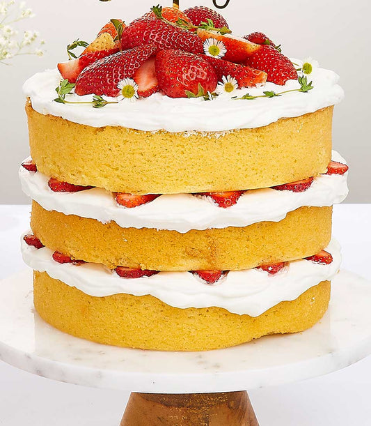 Triple-layer strawberry shortcake with whipped cream and fresh berries on marble stand