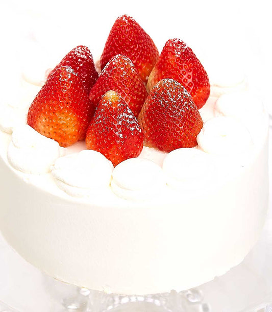 Whipped cream layer cake topped with fresh strawberries and powdered sugar, birthday celebration cake
