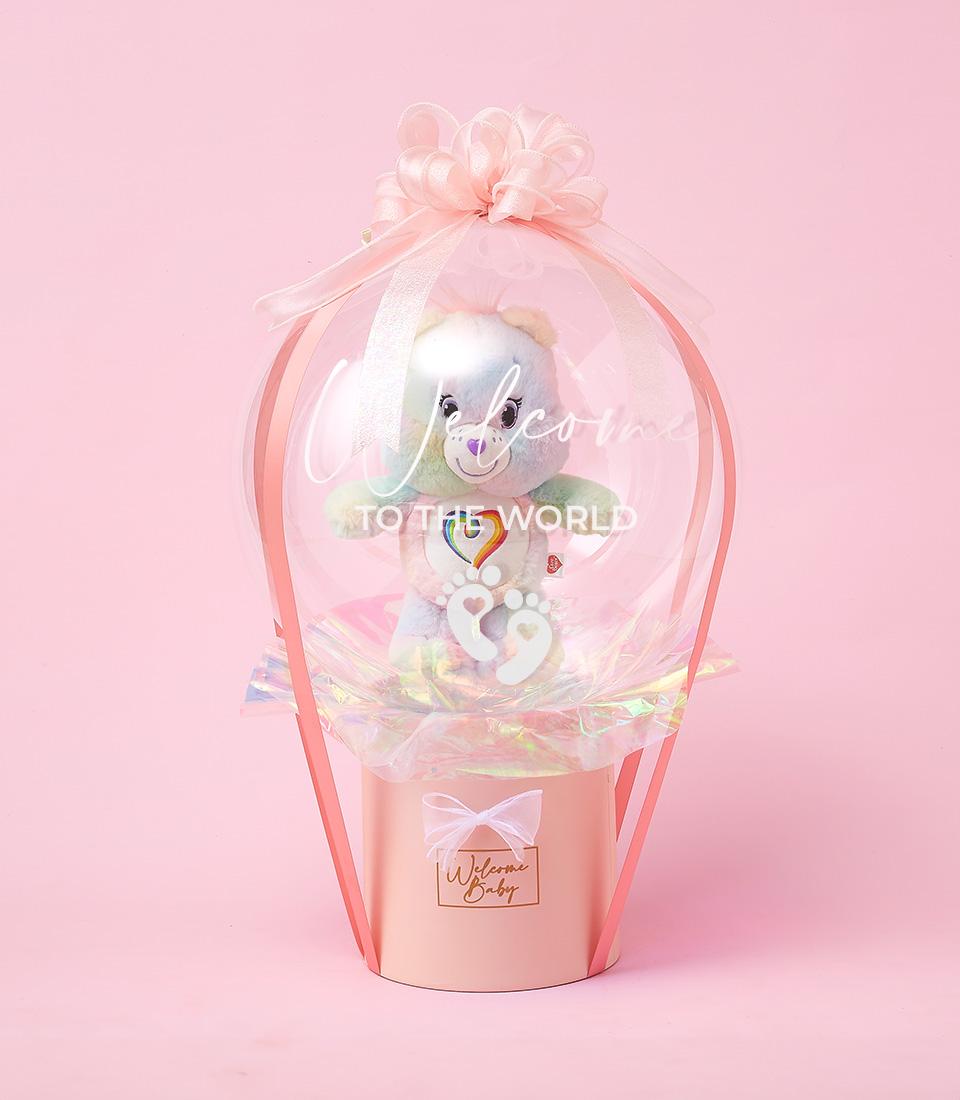 Pastel pink Care Bears plush toy in clear balloon with "Welcome Baby" gift box, newborn celebration hamper