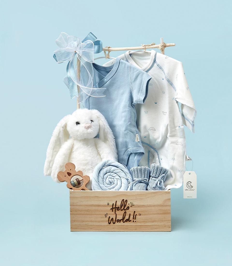 Light wooden newborn gift box with white plush bunny, blue onesies, swaddle blanket, and knitted booties