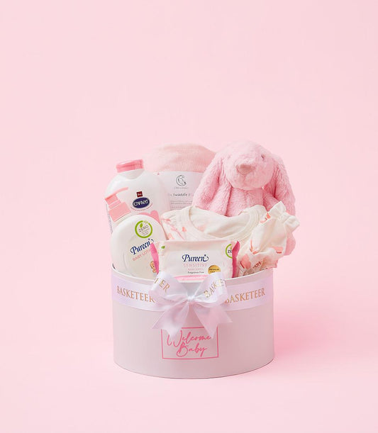 Gentle pink baby welcome gift box with swaddle blanket, plush bunny, lotion, and wipes