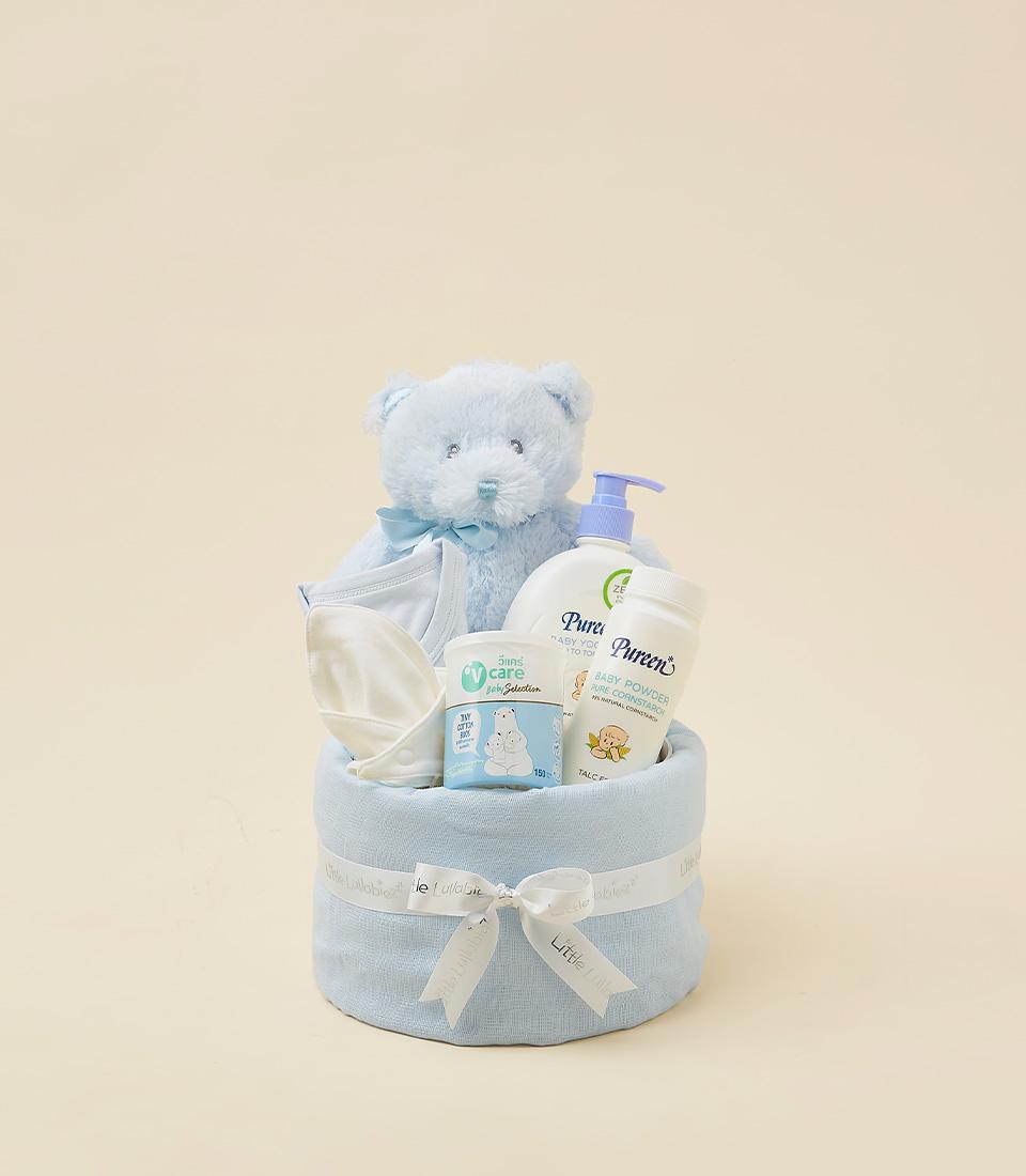Blue and white newborn gift hamper with plush teddy bear, onesie, baby wash, and powder in fabric basket