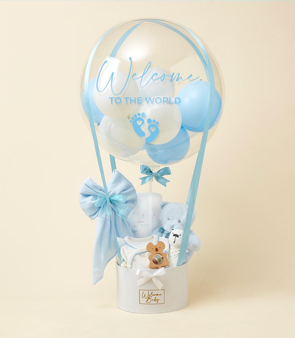 Blue and white hot air balloon newborn gift set with plush teddy, onesie, wooden rattle, and blanket