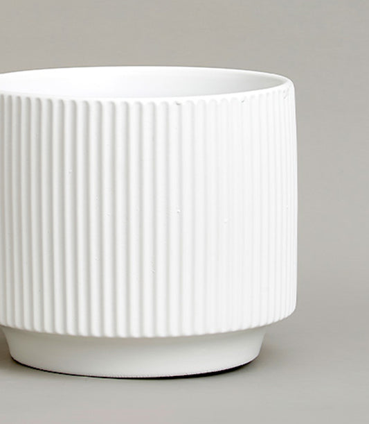 White ceramic vase with vertical ribbed design and minimalist aesthetic