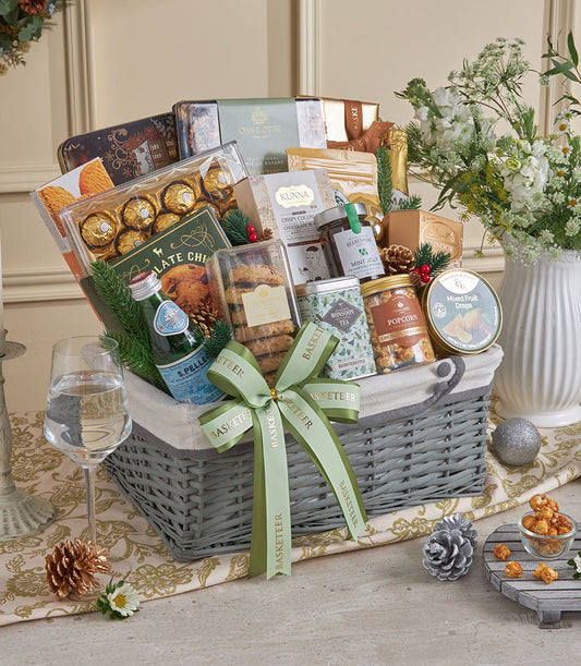 Gold-trimmed wicker gift basket with gourmet chocolates, cookies, and sparkling water for New Year celebrations