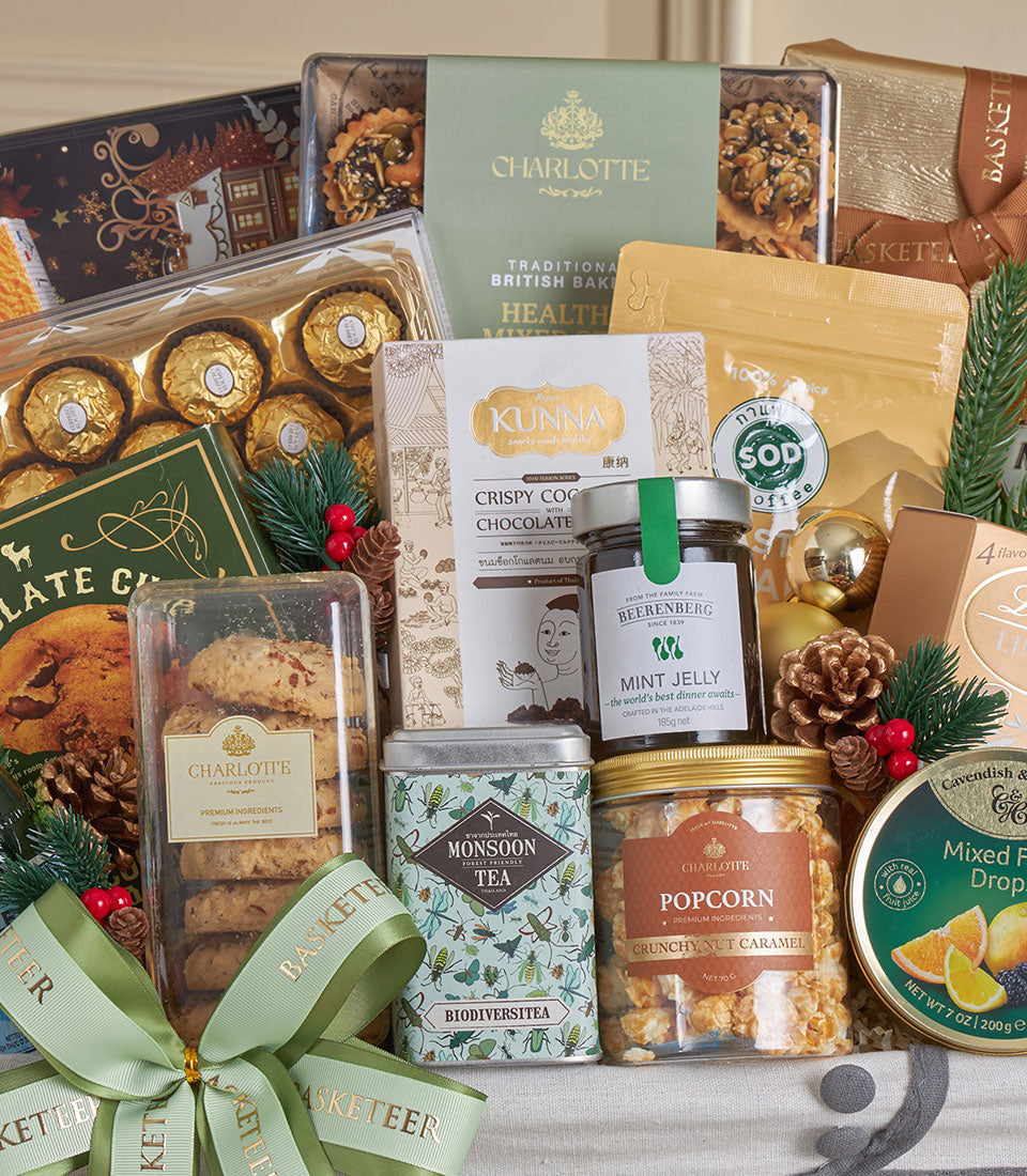 Gold premium celebration basket with gourmet cookies, tea, popcorn, jelly, and chocolates, tied with green ribbon and