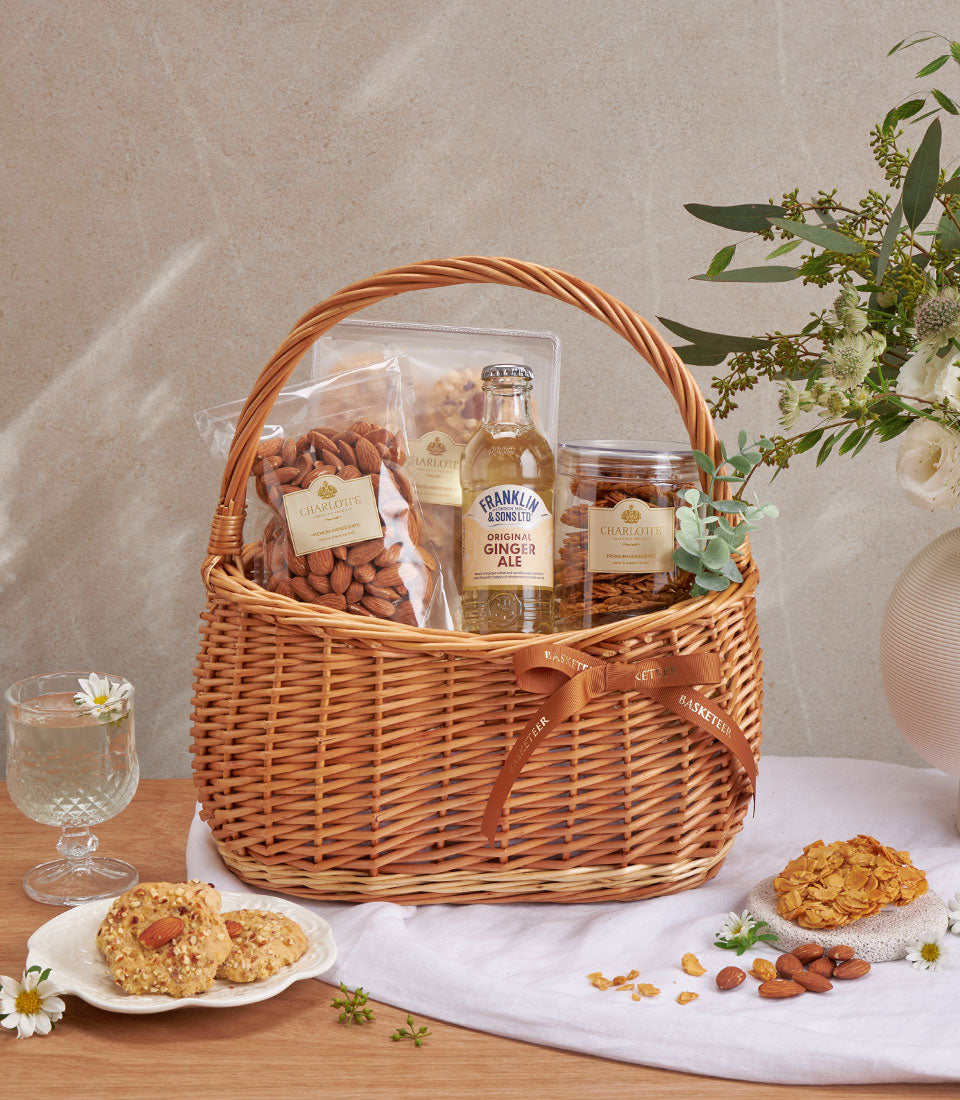 Woven gift basket with Charlotte almond cookies, roasted nuts, and ginger ale for premium wellness gifting