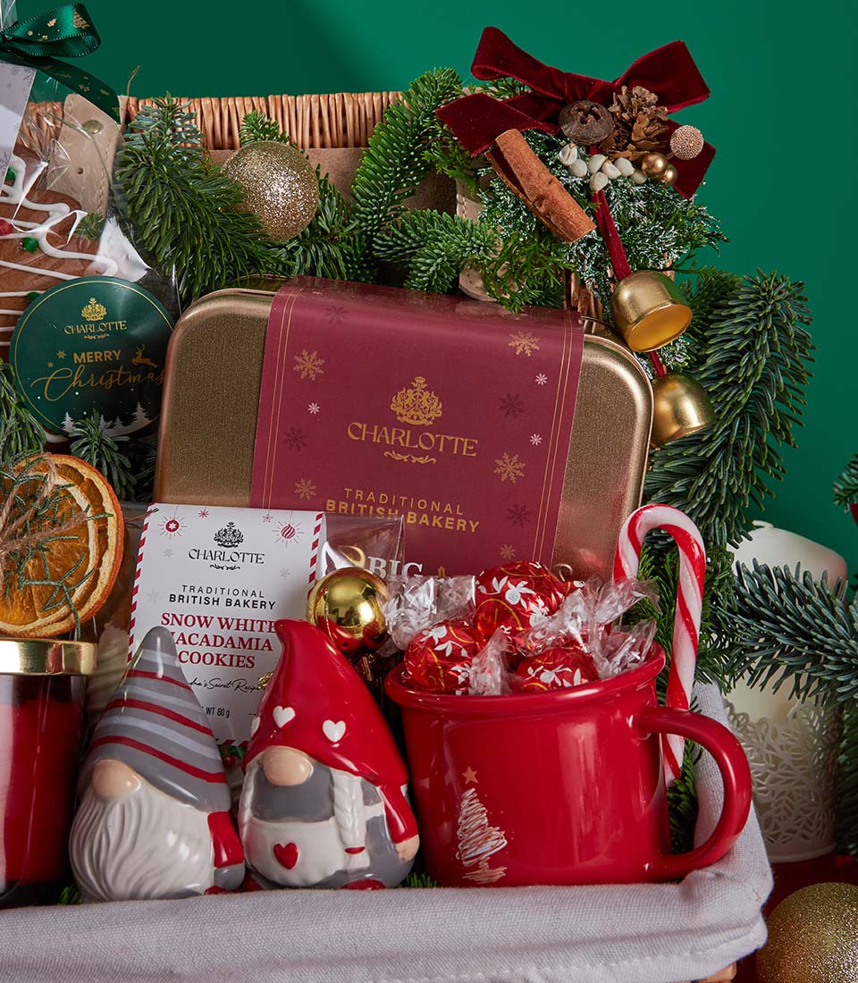 Festive Christmas gift basket with Charlotte Bakery cookies, ceramic gnomes, red mug, and gold ornaments