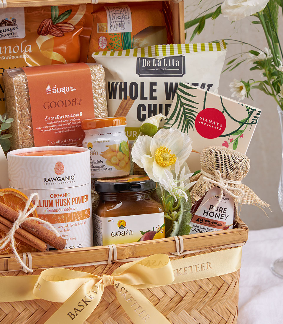 Premium wellness gift basket with organic rice, whole grain snacks, chocolate, psyllium husk, honey, and ginger in woven