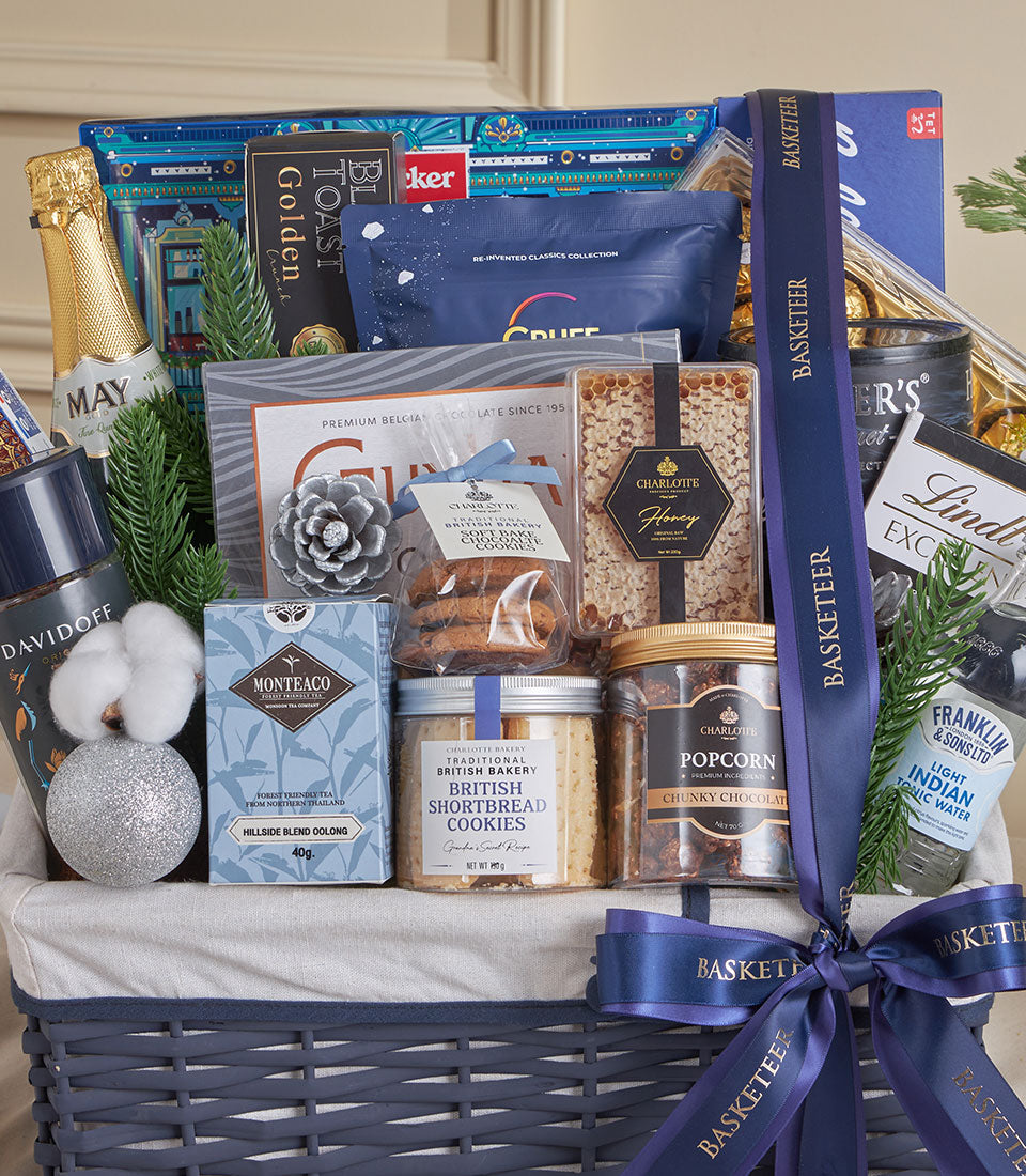 Blue woven gourmet gift basket with champagne, Belgian chocolate, shortbread, and premium tea for New Year celebrations