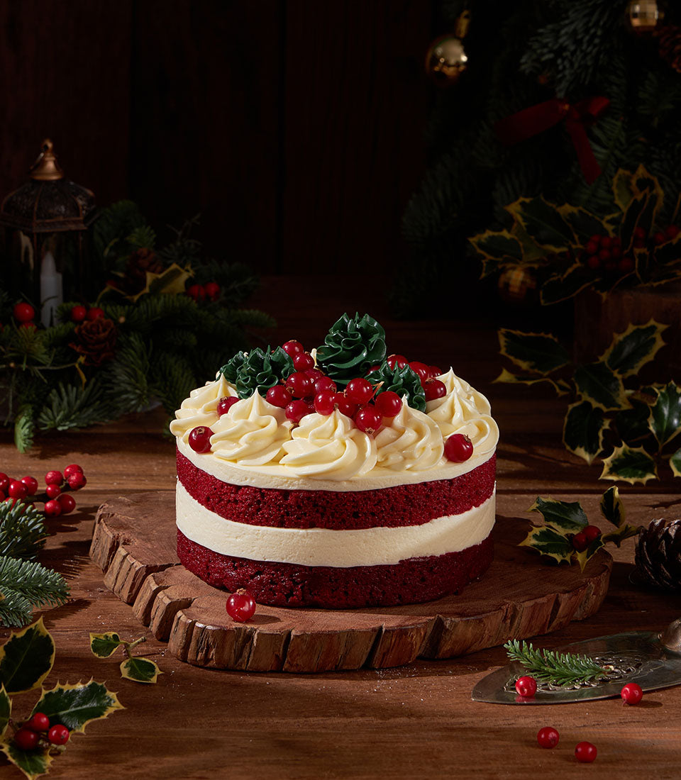 Artisan red velvet cake from Charlotte Bakery, a British bakery in Thailand. Cream cheese frosting, red currant berries and green pine decorations. Order custom cake Bangkok.