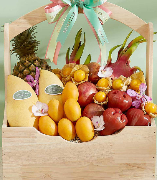 Premium Thai tropical fruits gift basket with mangoes, pineapple, dragon fruit, and orchid accents in wooden hamper