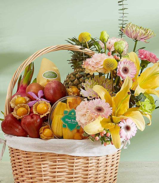 Woven wicker basket filled with premium Thai tropical fruits, fresh flowers, and organic fruit selection with yellow mango,