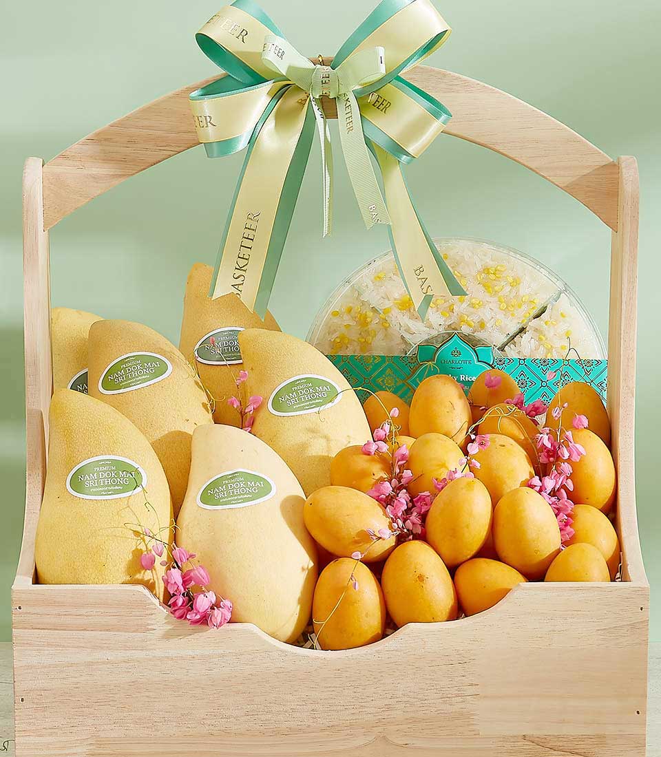 Premium wooden gift basket with fresh yellow mangoes, apricots, delicate pink flowers, and sticky rice dessert with cream