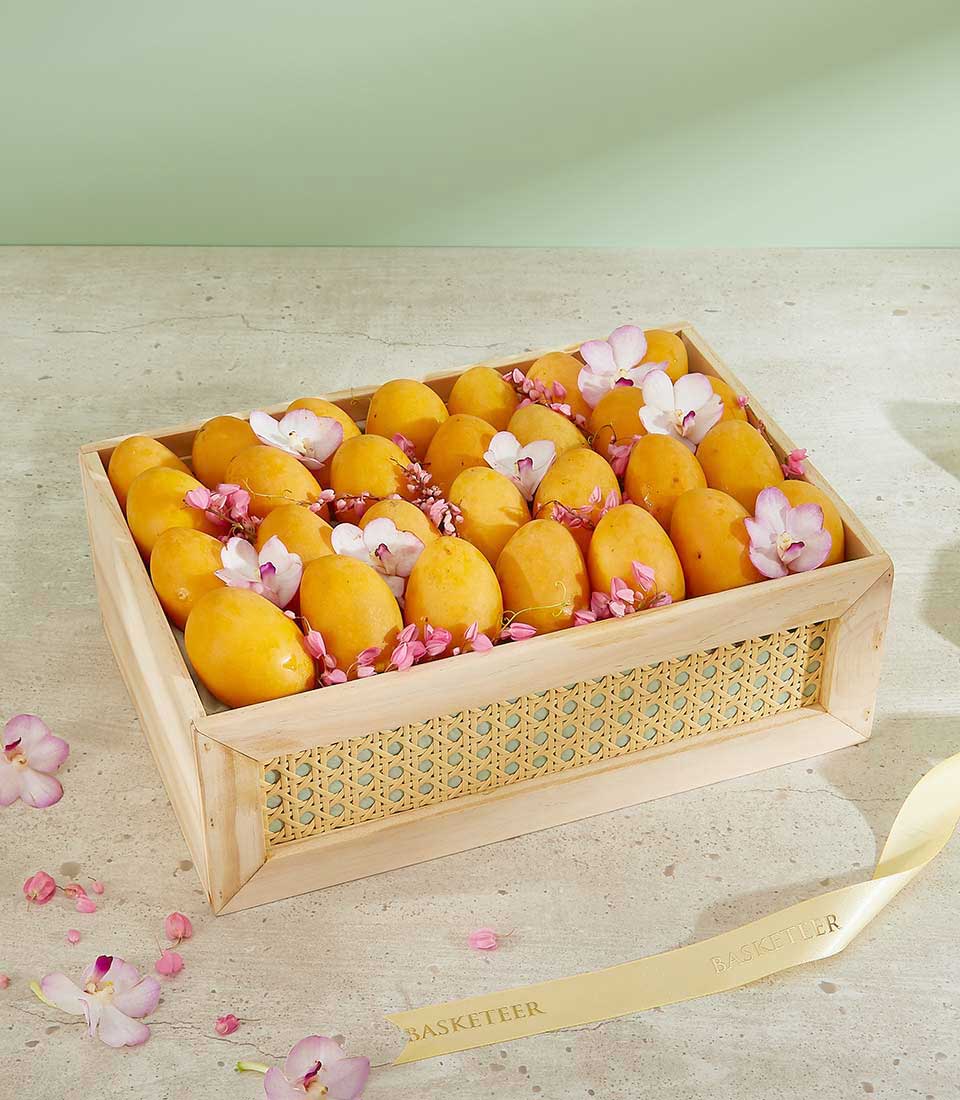 Premium wooden gift box with ripe yellow mangoes, pink flowers, and white orchids arranged inside