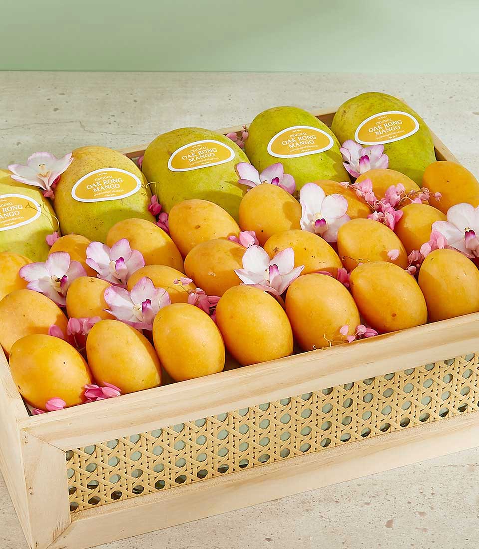 Wooden gift box with fresh tropical mangoes, white and purple orchids, and pink petals