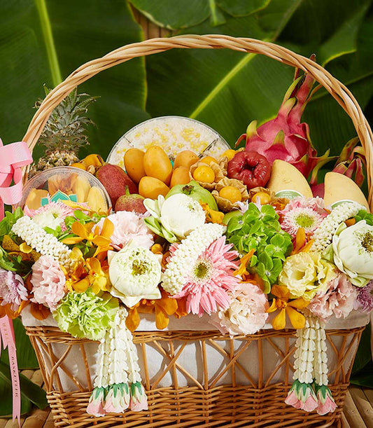 Woven wicker gift basket overflowing with tropical fruits, fresh flowers, and Thai garlands for Songkran celebration