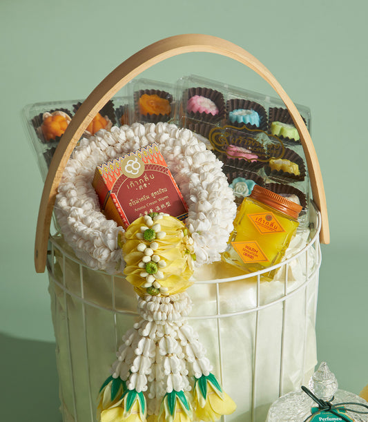 Thai Songkran blessing gift basket with white woven garland, aroma cream, gourmet treats, and fragrant bottle