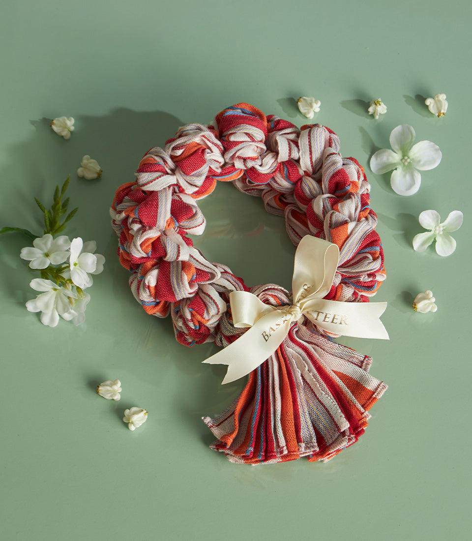 Songkran blessing wreath with red, orange, white and blue fabric strips, cream satin bow, and jasmine flowers for Thai New