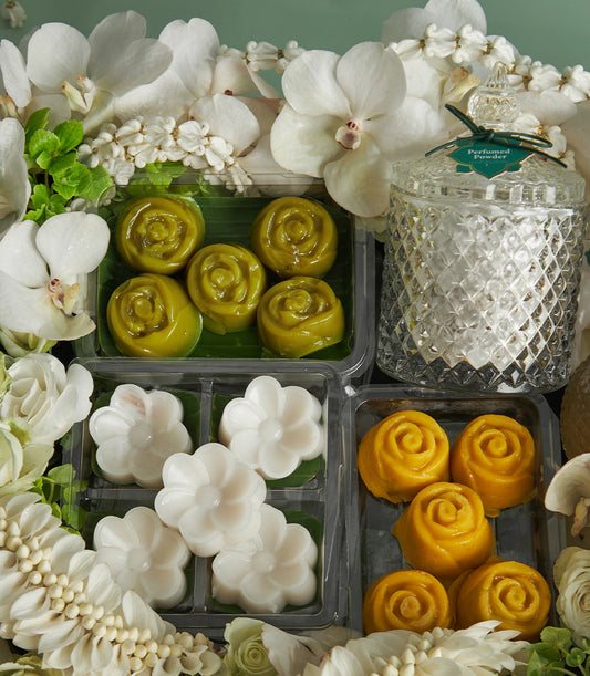 Thai Songkran gift set with traditional rose and flower-shaped sweets, perfumed powder jar, and white orchids