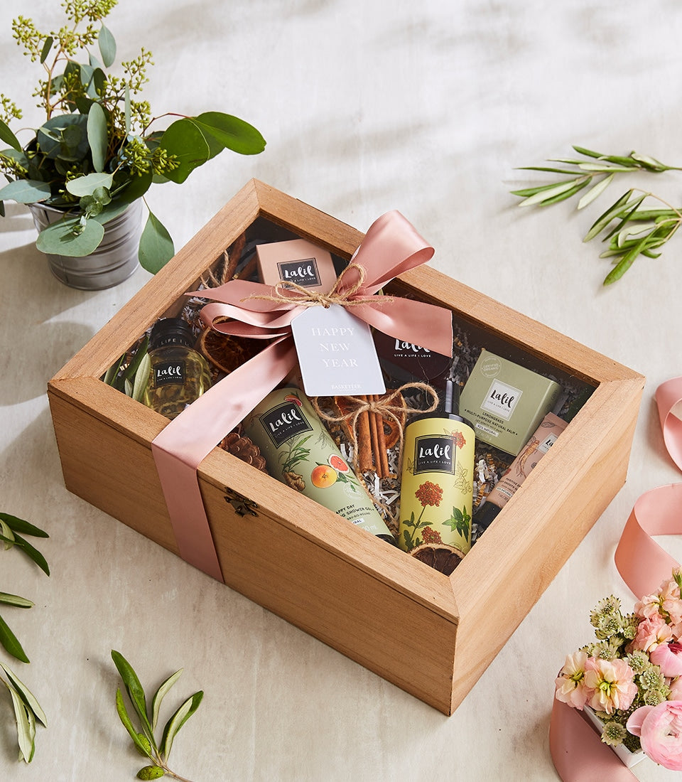 Wooden gift box filled with Lalil spa products, cinnamon sticks, and dried citrus, tied with pink satin ribbon for gifting