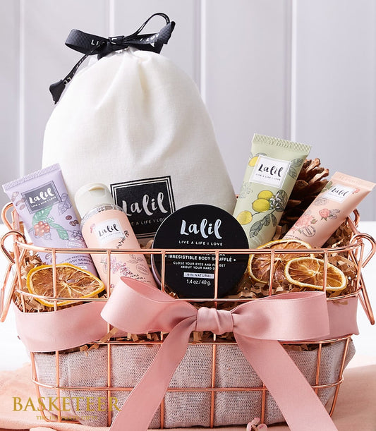 Luxury spa gift basket with rose gold wire container, cream drawstring bag, bath and body products, pink satin ribbon, and