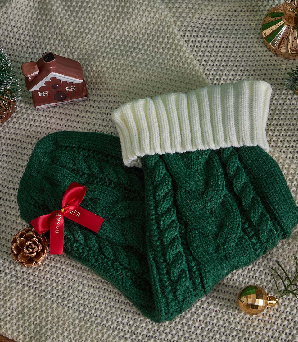 Green knitted leg warmers with festive Christmas decorations and gourmet gift basket styling
