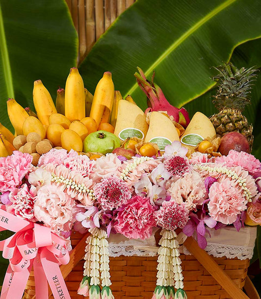Tropical Songkran fruit basket with mango, dragon fruit, pineapple, and pink carnations in woven hamper