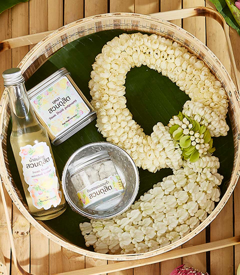 Fragrant Songkran garland set with white jasmine buds, scented water, and potpourri in woven bamboo tray