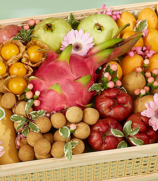 Vibrant Thai tropical fruits with dragon fruit, mangoes, and roses arranged in woven wooden crate