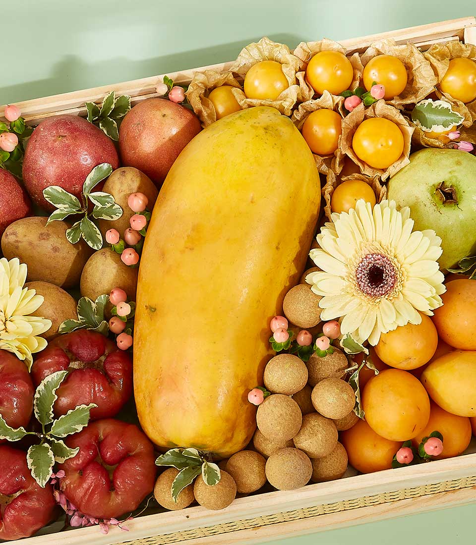 Wooden crate gift basket with tropical fruits including papaya, passion fruit, rose apples, longan, physalis, and kumquats,