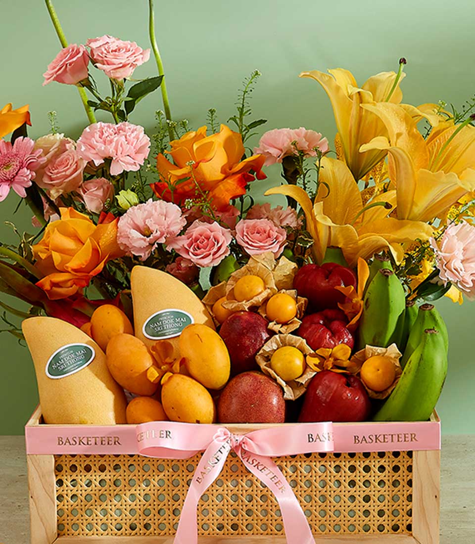 Tropical Harvest fruit and flower gift basket with Thai mangoes, roses, and lilies in woven rattan