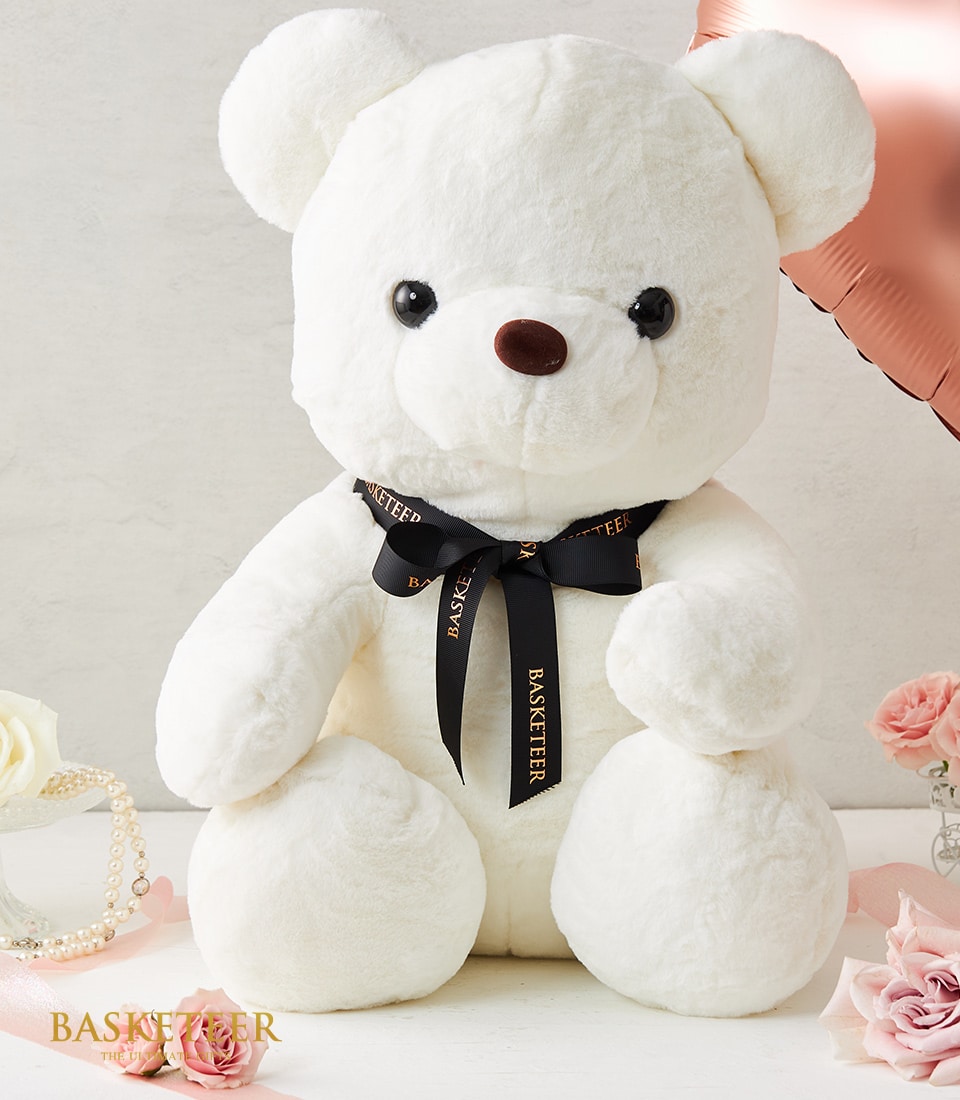 Large white fluffy teddy bear with ribbon bow, paired with fresh roses and luxury gift accessories