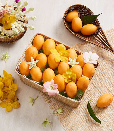 Golden-orange Marian plums in woven basket with orchids and jasmine garland