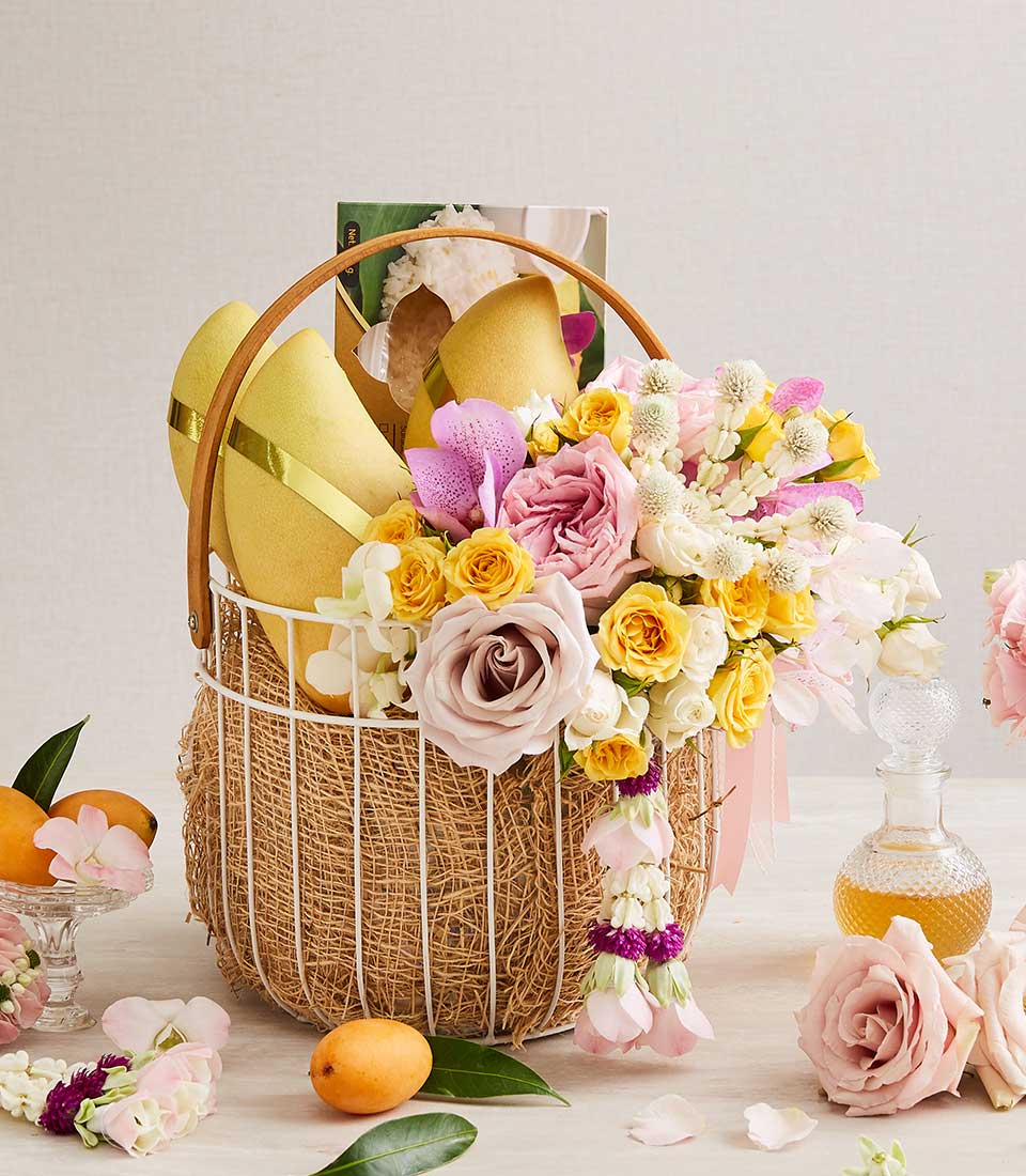 Thai New Year Songkran gift basket with golden mangoes, fresh roses and orchids, pink garland, and fragrant oil