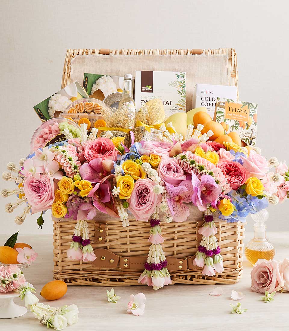 Wicker gift basket with Thai floral garlands, fresh roses and orchids, gourmet treats, and festive accents for Songkran