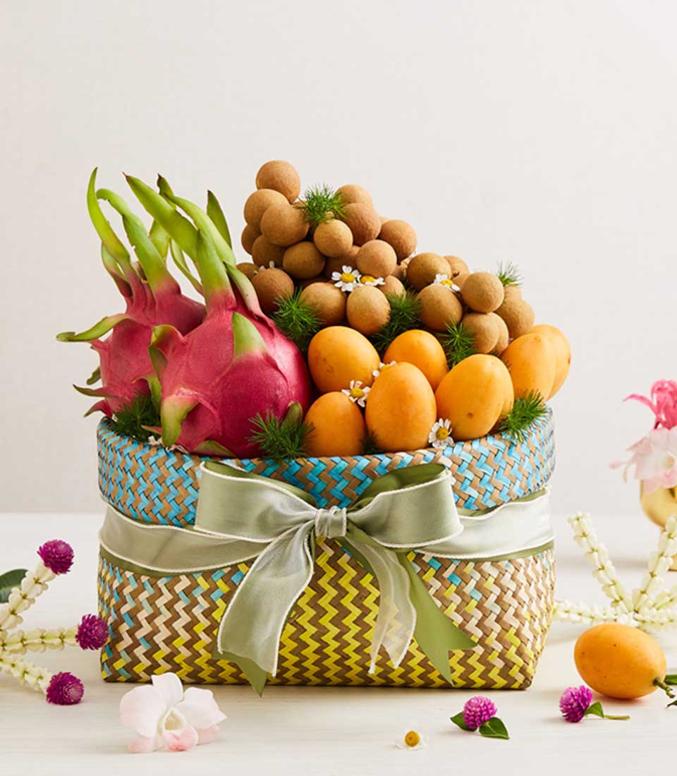 Vibrant woven fruit basket with dragon fruits, longans, and marian plums, tied with green ribbon