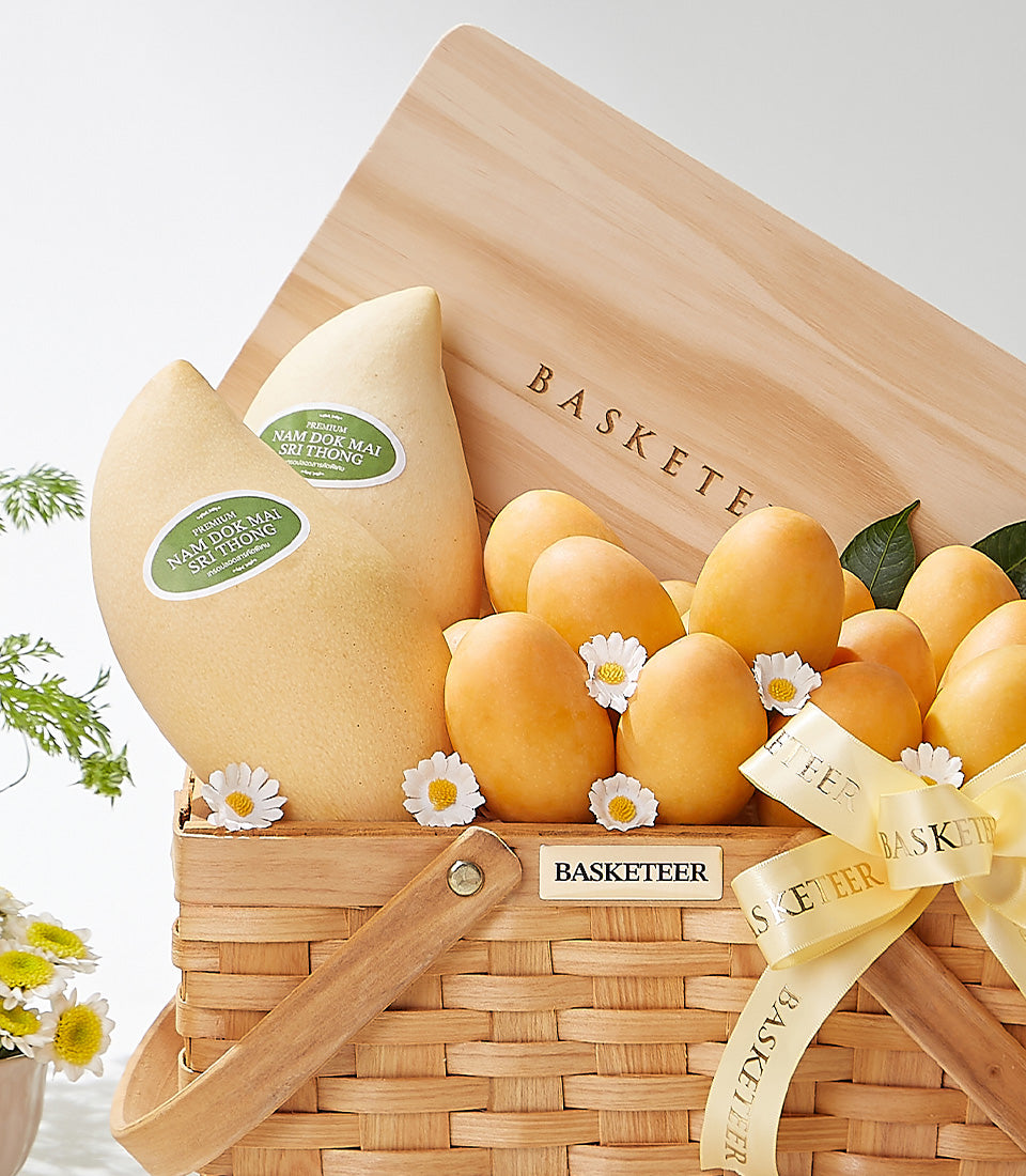 Woven wood gift basket with premium Nam Dok Mai mangoes, orange Thai fruit, and white daisies